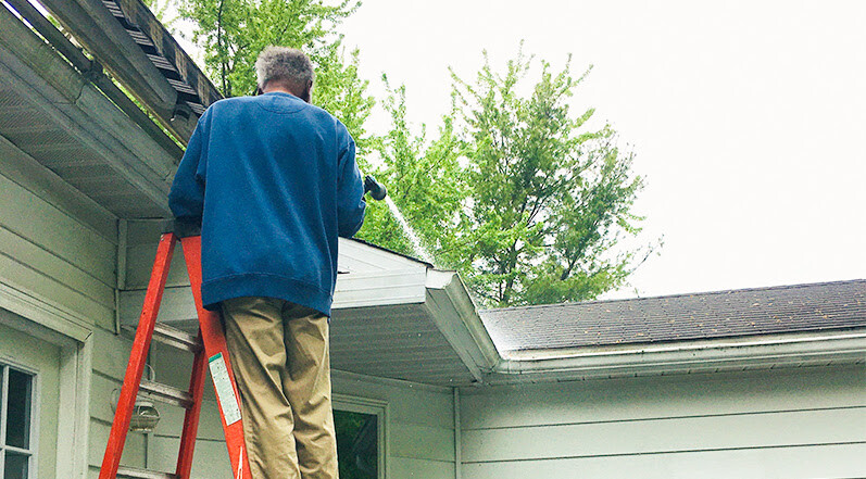 A Person Cleaning Their Gutters