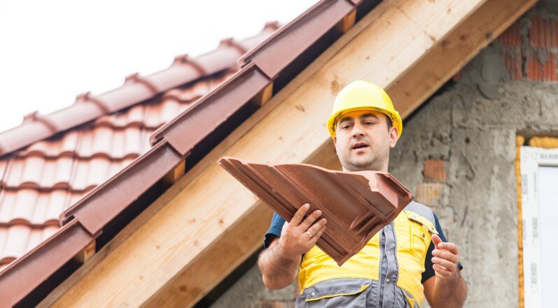 A Roofing Contractor Holding a Broken Shingle