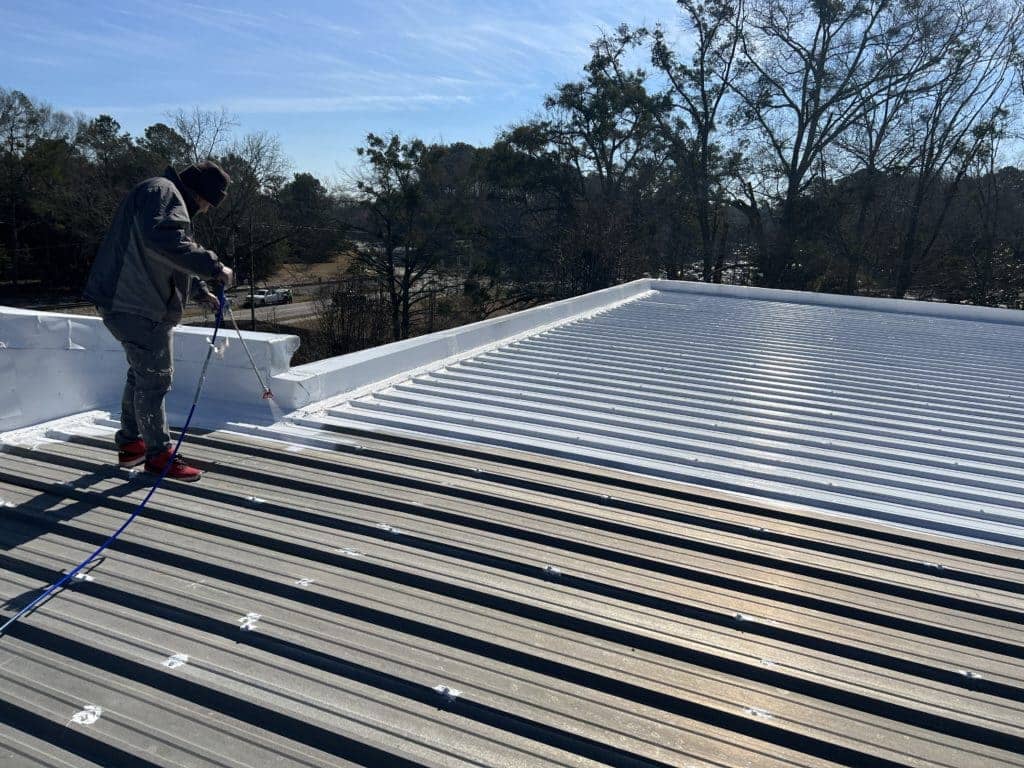 This image shows the process of roof coating on a metal roof.